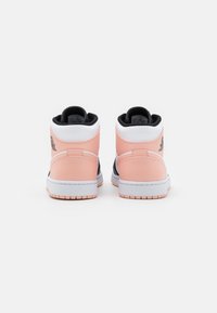 Para różowych, białych i czarnych wysokich sneakersów pokazana od tyłu na białej powierzchni z widocznym logo w okolicy pięty.