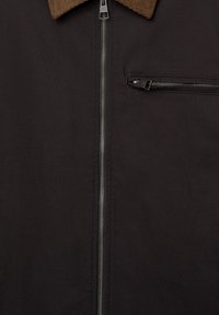 Black zip-up jacket, featuring a brown corduroy collar, front zip closure, and a small chest pocket with zip. Durable fabric texture.