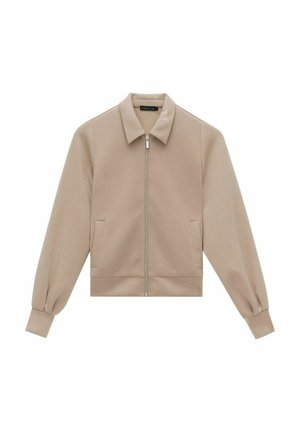 Beige lyhyt takki, jossa on kaulus, vetskari, pitkät puffihihat ja kaksi sivutaskua, valmistettu sileästä kankaasta.