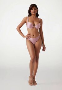 Světlé růžové spodní prádlo, které zahrnuje lehce vyztuženou podprsenku s nastavitelnými ramínky a odpovídající kalhotky s vysokými boky. Hladká tkanina a minimální detaily.