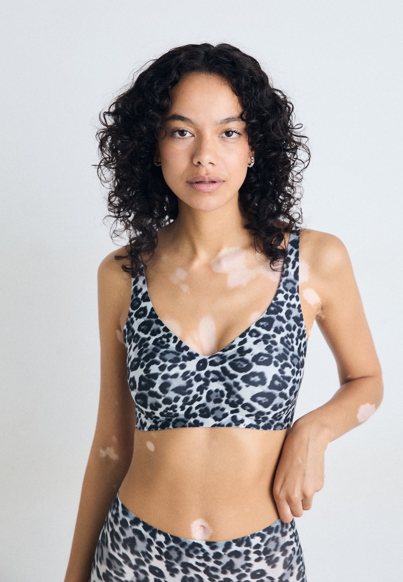 Bralette i leopardmønster med v-halsdesign, mykt stoff og brede stropper. Fargesammensetningen inkluderer nyanser av grått og svart.