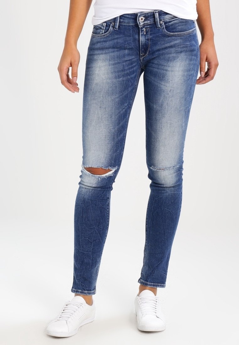 Smala denimjeans i mörkblått med en urtvättad look och knäsprickor. Materialet verkar texturerat med subtila sömnadsdetaljer och en klassisk femficksdesign.