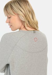 Grijze sweatshirt met een ronde halslijn, geribbelde manchetten en een ronde geborduurde detail in het rood aan de achterkant. Soepele textuur en casual pasvorm.