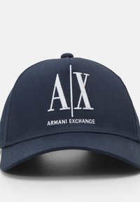 Cappellino da baseball blu navy in cotone, con logo ricamato bianco "A/X" e testo "ARMANI EXCHANGE" sul pannello frontale.
