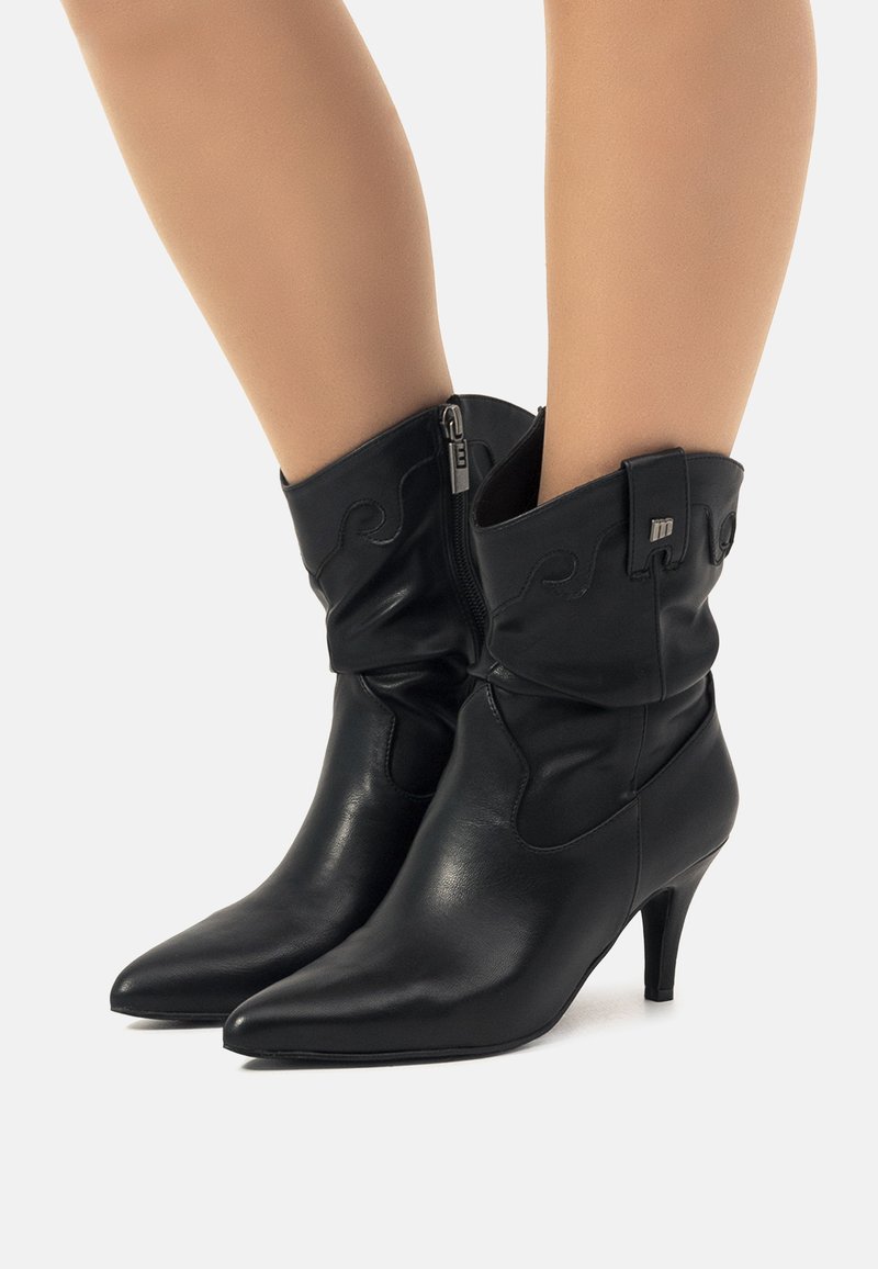 Botas de tobillo de cuero negro con un diseño arrugado, punta afilada y un tacón de 3 pulgadas; incluyen un cierre lateral y costuras decorativas.