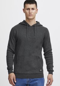 Gray hoodie with a front pocket, adjustable drawstring hood, ribbed cuffs, and hem. Made of a soft, textured fabric.