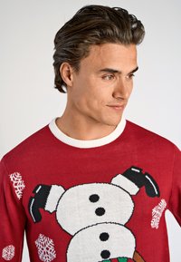 Czerwona sweter z wzorem bałwanka, dziergany z białymi i czarnymi akcentami, okrągłym dekoltem i wzorami płatków śniegu.