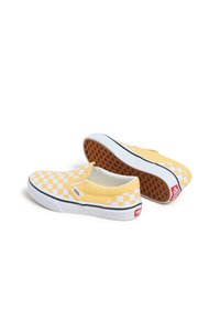 Geel dambord slip-on schoenen met witte rubberen zolen, voorzien van een gestructureerd bruin wafelpatroon op de buitenzool en een rode merkaccent.