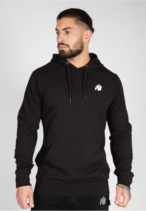 Zwarte b hoodie gemaakt van katoen, met een voorvak, trekkoord capuchon en een klein wit logo op de borst. Zachte textuur en standaard pasvorm.