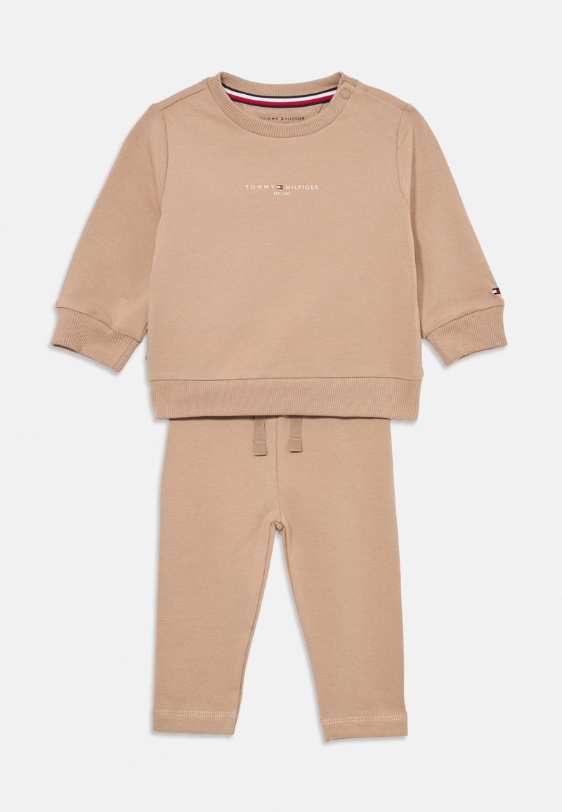 Beige Baumwoll-Trainingsanzug mit einem Langarmshirt mit Druckknöpfen an den Schultern, rundem Ausschnitt und passenden Hosen mit elastischem Bund und Knöchelabschlüssen.