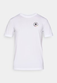 Balta kokvilnas T-krekls ar apaļu kaklu, īsām piedurknēm un apaļu logotipu ar melnu ērglu un tekstu kreisajā krūšu daļā.