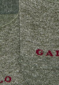 Calzini alla caviglia verde oliva realizzati in un tessuto a maglia testurizzato con il logo rosso "CALO" stampato vicino alla parte superiore. Design della punta rotonda.
