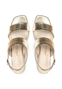 Sandalias metálicas doradas con dos correas anchas, diseño de punta cuadrada y una correa delgada en el tobillo. El interior es de un tono beige suave.