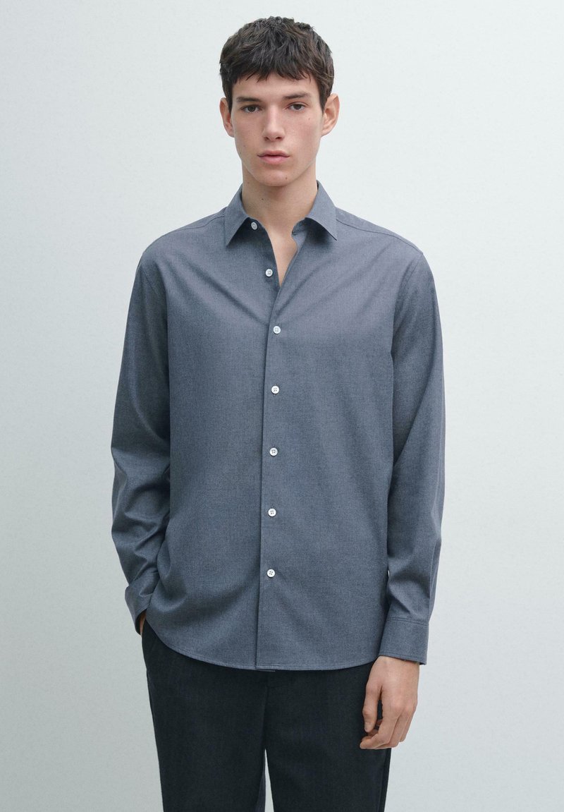 Šedá košile na knoflíky s špičatým límečkem, dlouhými rukávy a hladkou texturou. Má bílé knoflíky a upravený střih. Tenká látka.