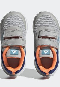 Šedé síťované tenisky s oranžovými a námořnickými akcenty, vybavené dvěma suchými zipy a modrým logem značky na jazyku. Kulatá špička, texturovaná podrážka.