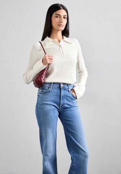Off-white ribbed long-sleeve top with a collared neckline, paired with light blue high-waisted jeans, and a small woven burgundy shoulder bag.