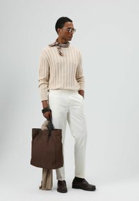 Beige geribbelde trui, witte getailleerde broek, bruine tas, sjaal met patroon, bruine leren schoenen; modern, minimalistisch design.