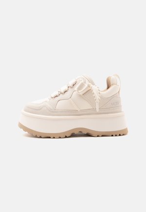 Baskets à plateforme beige avec une semelle épaisse, des lacets texturés, un col rembourré à la cheville et un marquage UGG sur le côté et la languette du talon.
