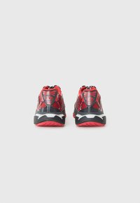 Red and black athletic shoes with mesh upper, padded collar, and contrasting white sole. Treaded rubber outsole for grip. Reflective accents.
