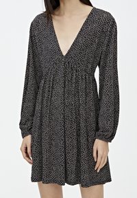 Czarna sukienka z długimi rękawami, głębokim dekoltem w kształcie V i kwiatowym wzorem. Luźny krój z marszczonym talią i fakturowanym materiałem, odpowiednia na codzienne wyjścia.