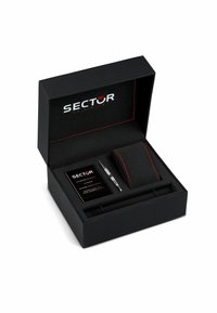 Scatola regalo nera con superficie testurizzata e cuciture rosse. Include un cuscino in velluto nero, una penna argentata e una scheda prodotto. Marchio: SECTOR.