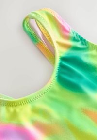 Többszínű fürdőruha sima textúrával, zöld, rózsaszín és sárga színátmenetes mintával. Vékony pántokkal és varrott szélekkel.