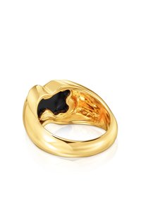 Anello color oro con superficie liscia e lucida; presenta una forma nera accentuata al centro; bordi arrotondati; banda leggermente spessa.