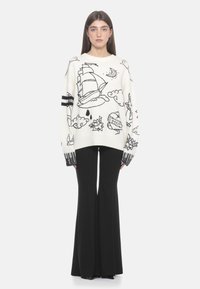 Übergroßer weißer Pullover mit schwarzem nautischem Stickdesign, das Schiffe und Wolken zeigt, sowie gerippten schwarz-weißen Bündchen. Kombiniert mit schwarzen ausgestellten Hosen.