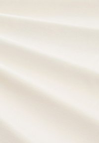 Lichtcrème stof met een gladde textuur, voorzien van zachte plooien en een subtiele glans. Geen zichtbare patronen of hardware-details.