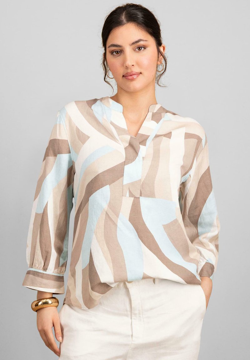 Blusa leggera e stampata con onde beige, marroni e blu chiaro. Collo a V e maniche lunghe con polsini arricciati.