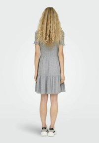 Grå räfflad klänning med korta ärmar, lager-på-lager volangkant och avslappnad passform. Bärs med vita sneakers med svarta detaljer.