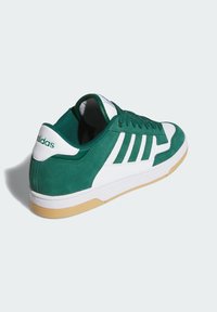 Zelene suede tenisice s bijelim kožnim naglascima, s teksturiranim gornjim dijelom od tkanine, dizajnom s tri pruge i gumenom gumicom.