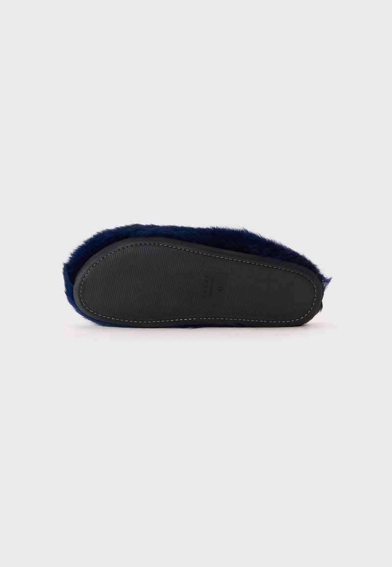 Dunkelblaue, flauschige Hausschuhe mit strukturiertem Obermaterial und einer schwarzen Gummisohle. Sie verfügen über einen genähten Rand und ein flaches Design für komfortable Passform.