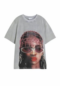 Šedé voľné tričko s grafick�ým motívom tváre v slnečných okuliaroch, s vrkočmi a ozdobou z korálkov. Bavlnený materiál.