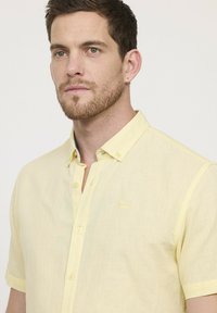 Korte mouwen gele button-up overhemd gemaakt van een lichtgewicht stof, met een pocket en een klein geborduurd logo op de borst.