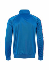 Blå atletisk jakke med høj krave, lange ærmer, sidestriber med røde accenter og en glat, let tekstur af stoffet.