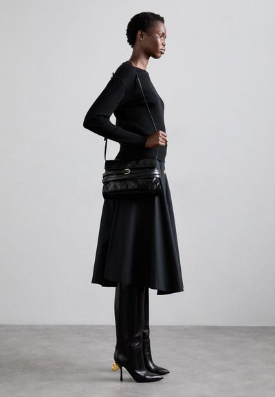 Melnas ribotas džemperis, melna A formas svārki, ceļgalu augstuma melni zābaki ar zelta akcentiem un melna ādas crossbody soma. Vienkārša, eleganta silueta.
