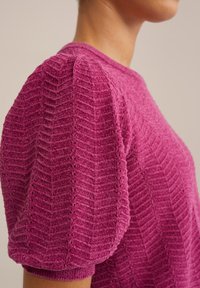 Maglione lavorato a maglia rosa testurizzato con motivo a zigzag, scollatura rotonda e maniche a sbuffo con polsi in costina.