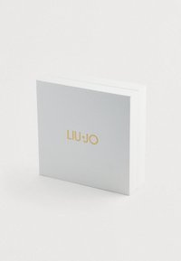 Négyzet alakú, fehér textúrájú doboz arany "LIU·JO" logóval a közepén, sima fehér háttér előtt.