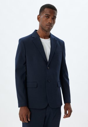 Blazer azul marino hecho de una tela suave, con un diseño de un solo botón, dos bolsillos frontales rectos y cierre de botón.