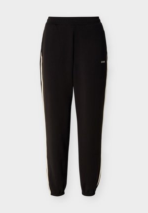 Pantalones jogger negros con rayas laterales blancas, cintura y puños elásticos, y pequeño logo blanco de "GUESS" en la parte superior izquierda de la pierna.