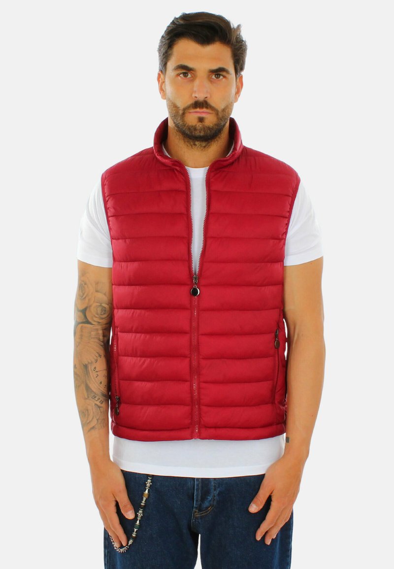 Gilet imbottito rosso in nylon, con colletto alto, zip frontale e tasche ai lati, indossato sopra una T-shirt bianca.