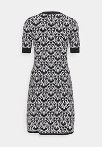 Robe à manches courtes noir et blanc avec une taille cintrée, présentant un motif floral abstrait répétitif et des bordures noires sur les manches et l'ourlet.