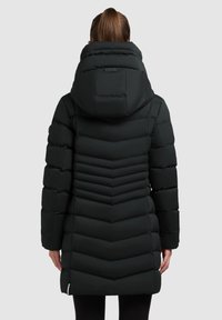 Čierna vypchávkovaná bunda s vysokým golierom, s vzorom chevron a hladkou textúrou. Dlhé rukávy a mierne zúžený lem.