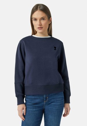 Granatowy sweter z okrągłym dekoltem, prążkowanymi mankietami i dołem. Posiada małe czarne haftowane logo po lewej stronie klatki piersiowej.