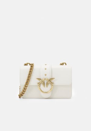 Borsa a mano in pelle bianca con tracolla a catena dorata e fibbia dorata con due uccelli che si guardano in un dettaglio ad anello.