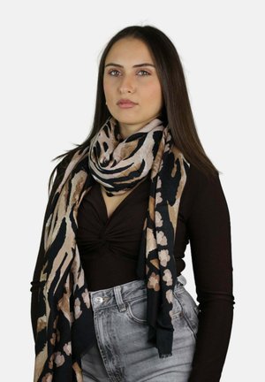 Sciarpa animalier in tonalità di nero, beige e rosa chiaro; tessuto morbido con drappeggio fluido; indossata su una camicetta scura aderente.