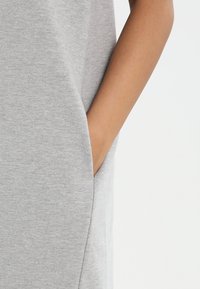Robe en coton gris avec une coupe ample et des poches latérales. Possède une texture lisse et un design simple et minimaliste.