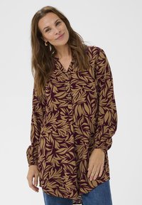 Långärmad blus i vinröd med ett lövmönster i beige, med V-ringning, knapppdetaljer och elastiska ärmslut.