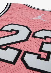 Roze sportshirt met zwarte en witte accenten, voorzien van groot wit nummer 23 met zwarte omlijning en een witte Jumpman-logo vlakbij de kraag.